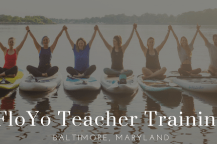 A group of people all on paddle boards sitting while grasping hands