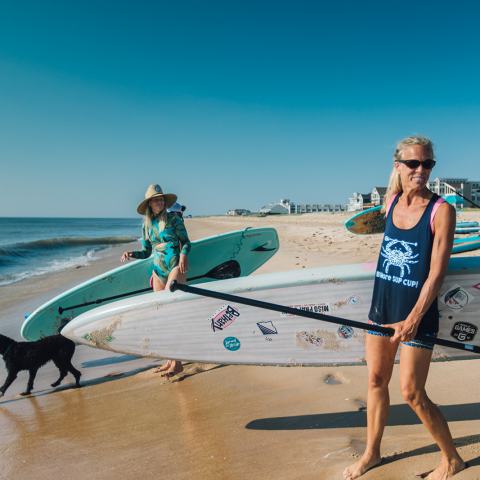 a person walking on a beach holding a surf board