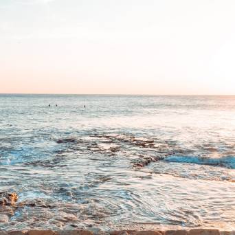 a man walking across a beach next to the ocean