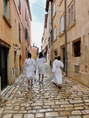 a group of people walking down a street next to a brick wall