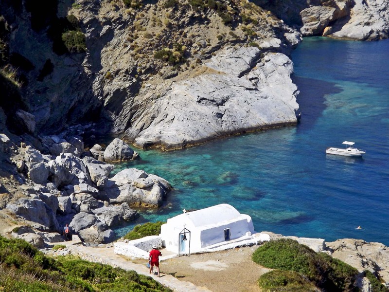 a rocky cliff with water and a mountain in the background