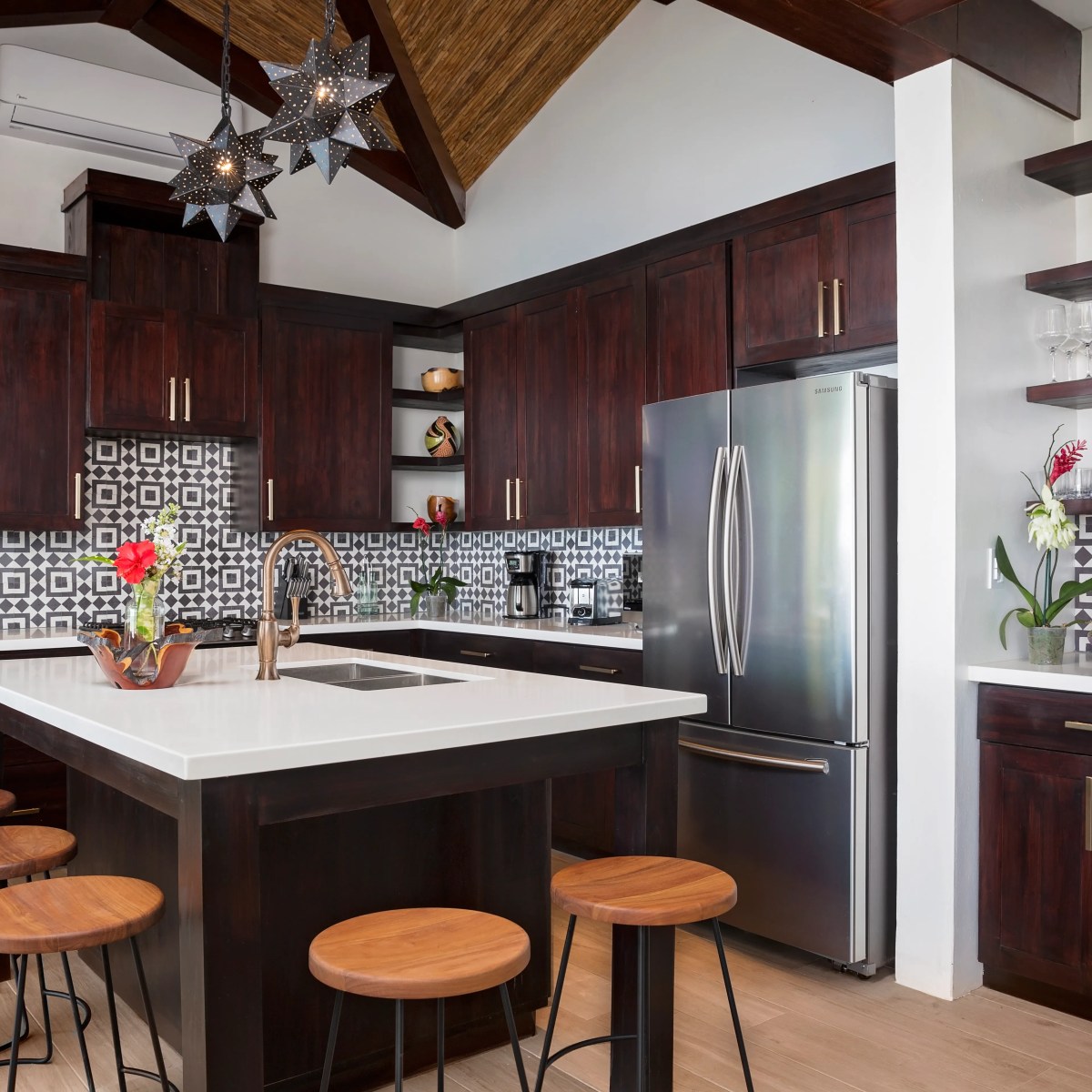 Modern kitchen with island, dark wood cabinets, patterned backsplash, and bar stools.