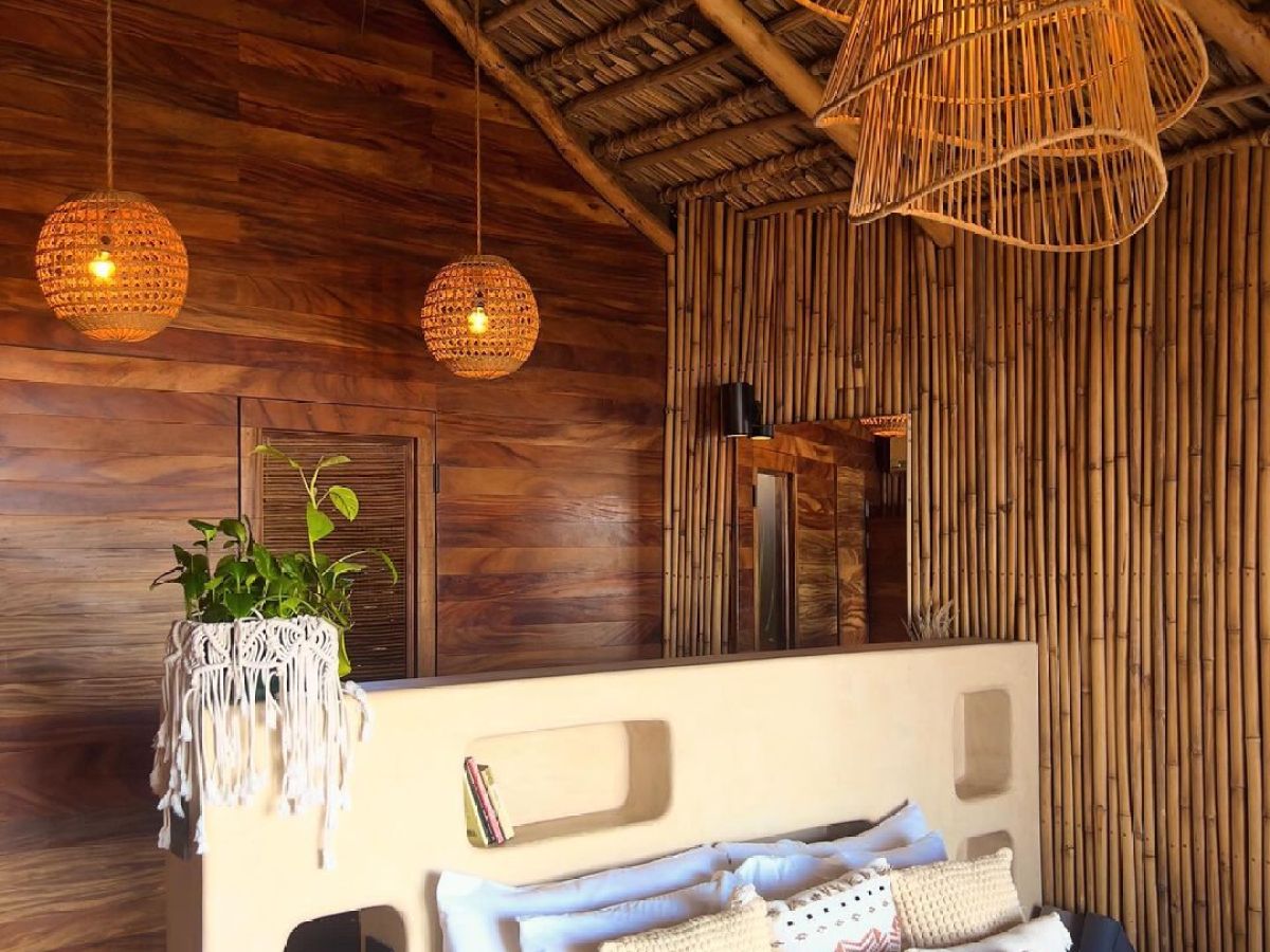 Rustic bedroom with bamboo decor, cozy bed, woven pendant lights, and plant on headboard in tropical theme.
