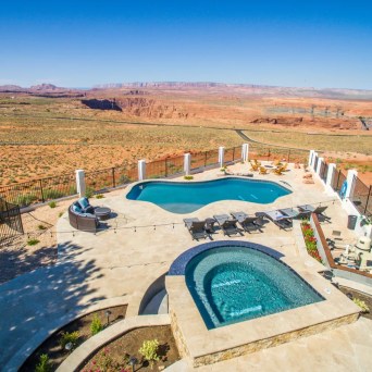 Aerial view of a pool and hot tub overlooking a desert landscape and canyon.