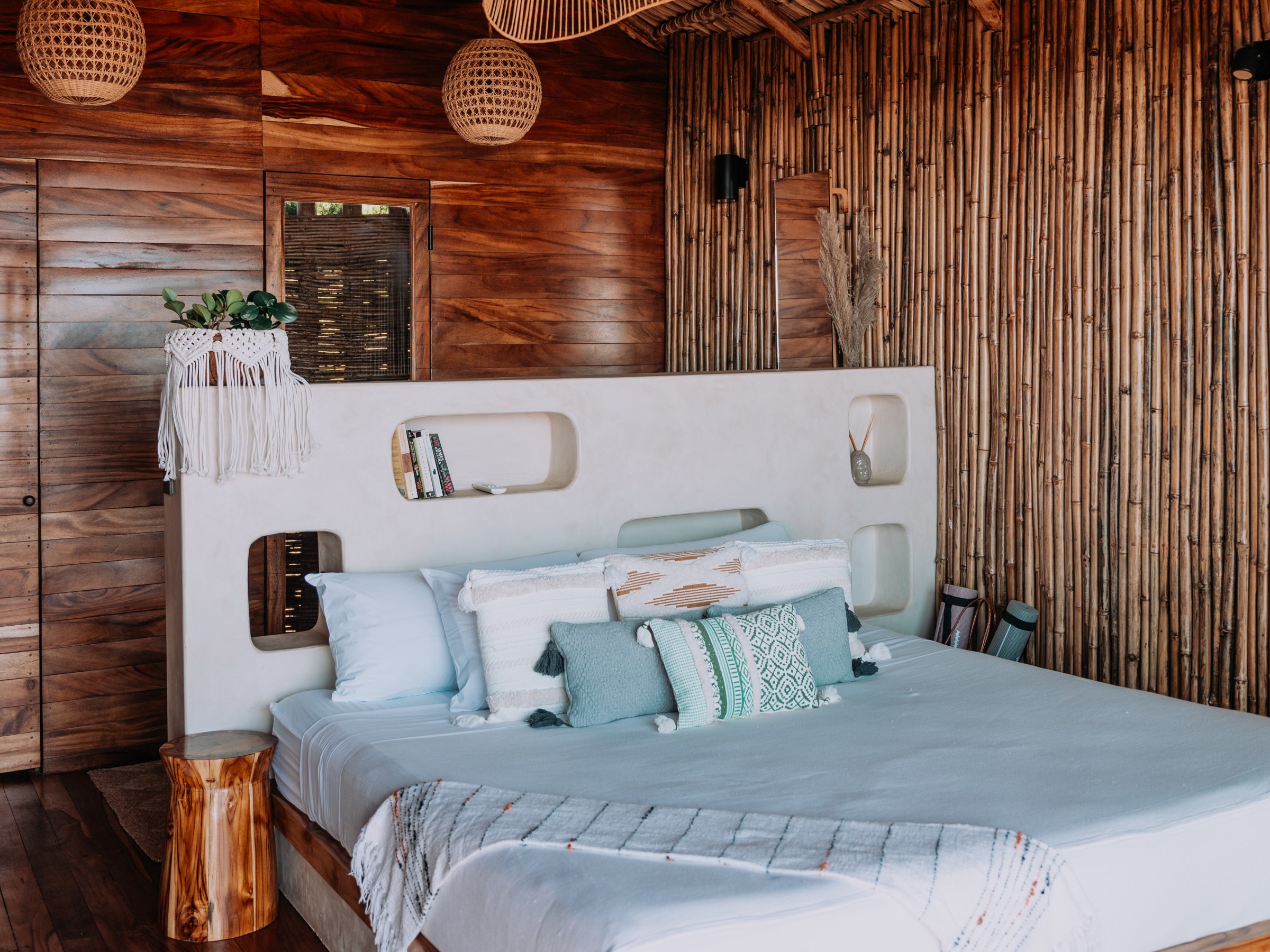 Rustic bedroom with wooden walls, canopy bed, and woven light fixtures.
