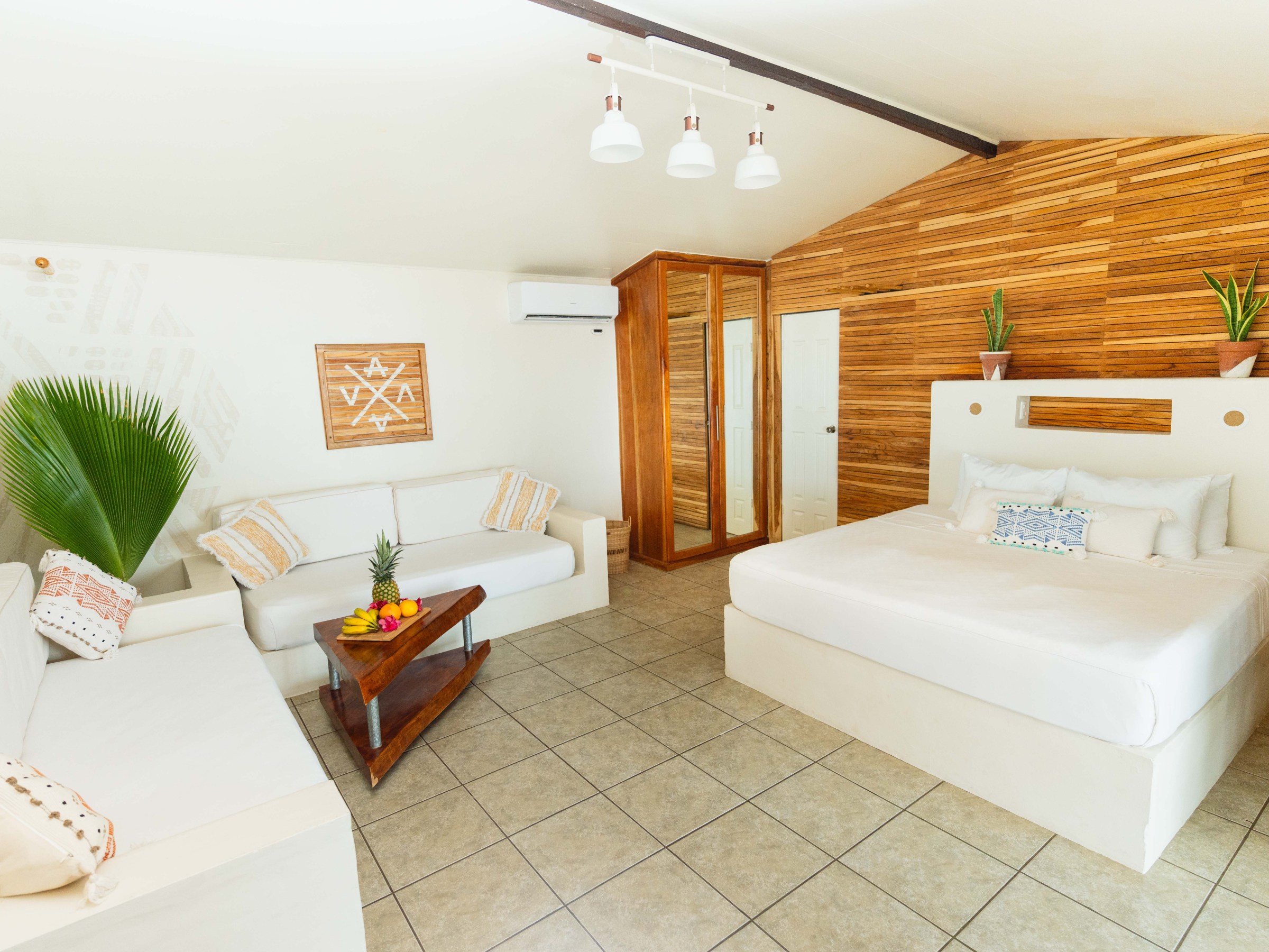 Spacious modern bedroom with wooden accents, white furniture, and plants.