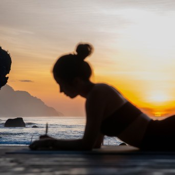 Silhouette of a person writing on a beach at sunset.
