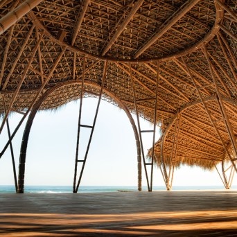 Open bamboo pavilion with ocean view, thatched roof, and wooden floor.