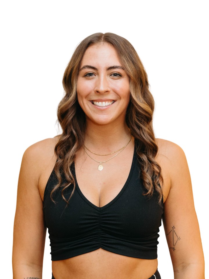 Smiling person with long wavy hair, wearing a black crop top and necklaces.