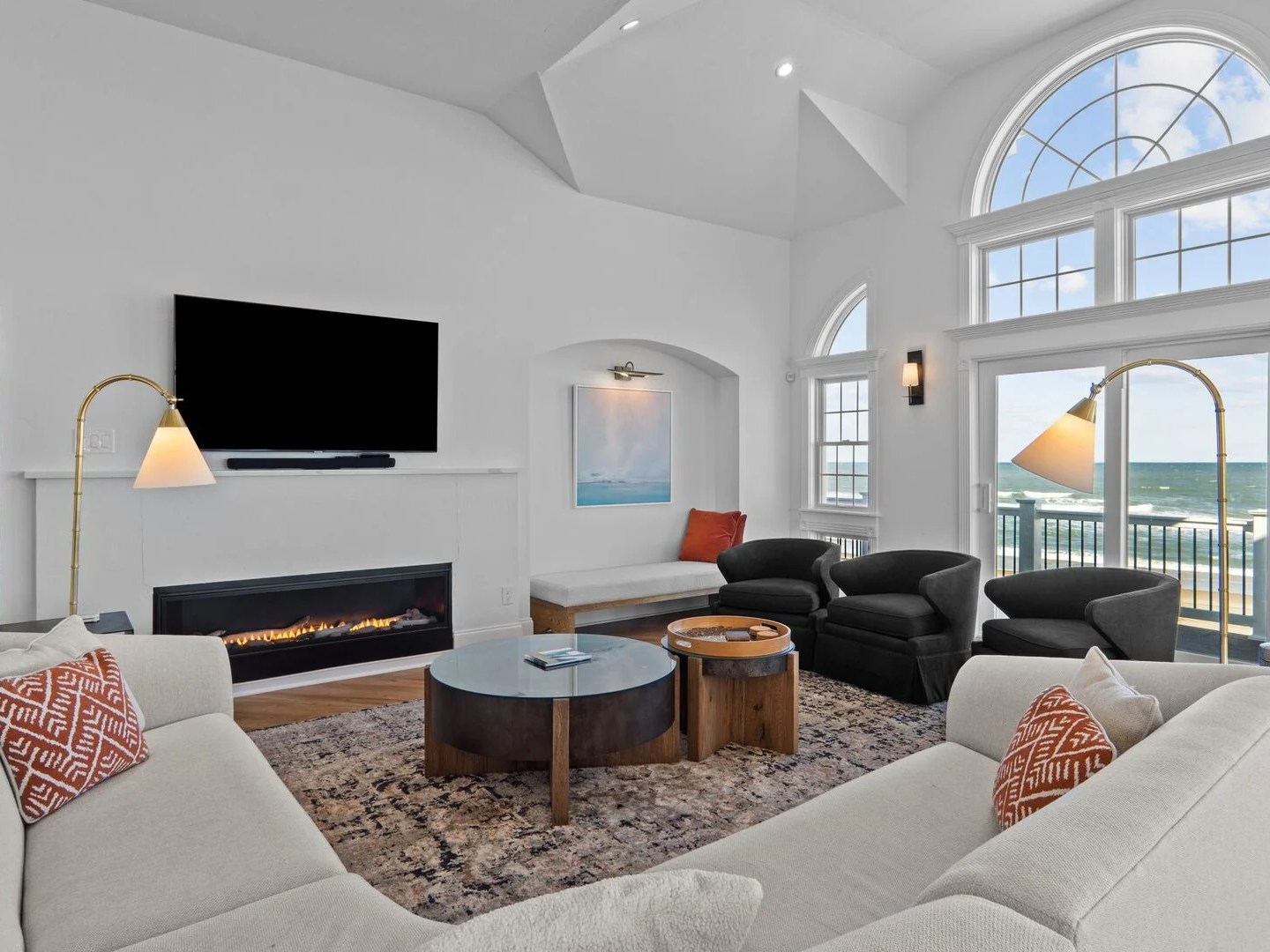 Bright living room with ocean view, modern furniture, and a large window.