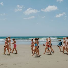 A group of people walking on a beach with the ocean in the background.
