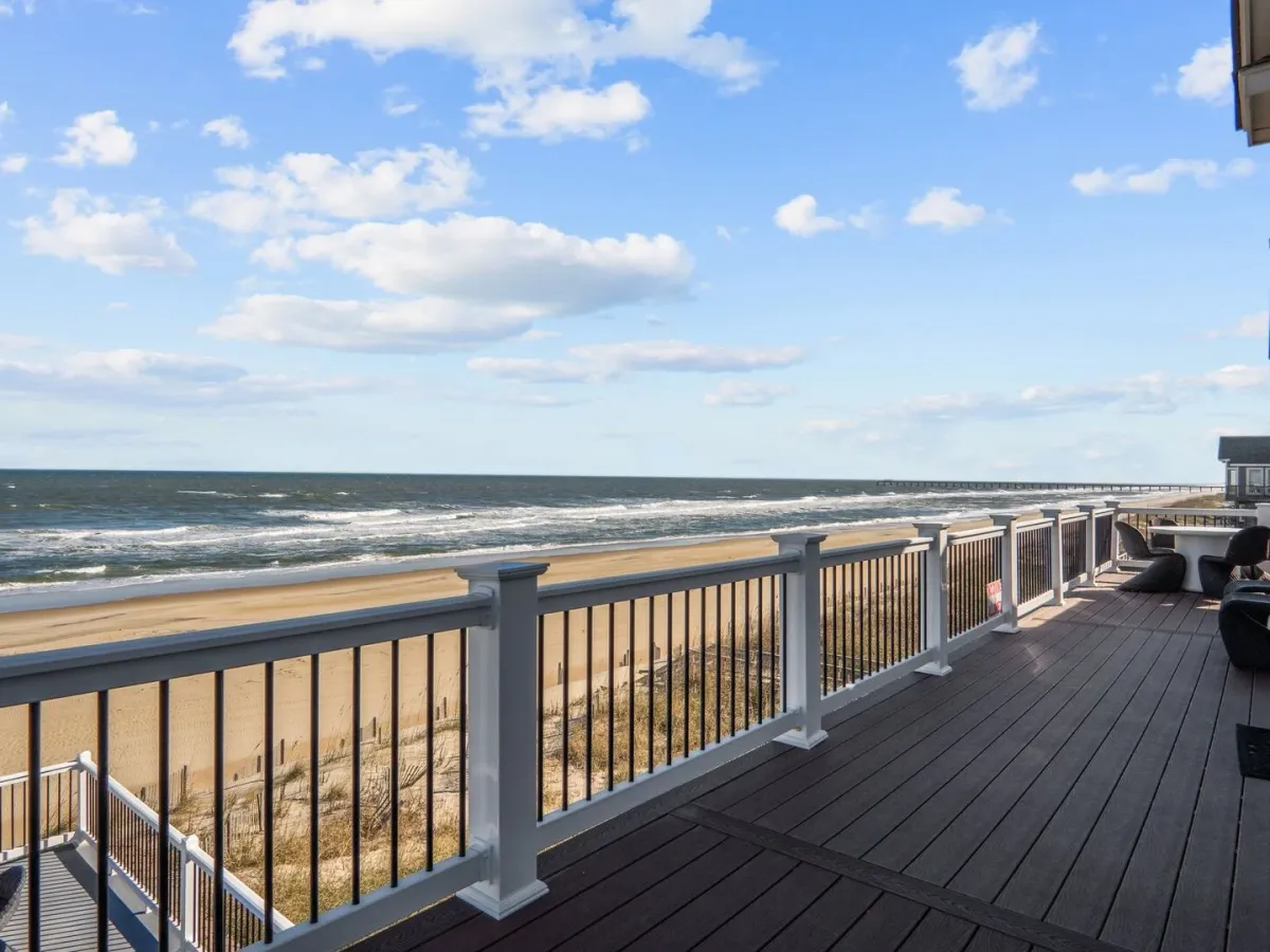 Beachfront deck with railing, ocean view, and outdoor furniture.
