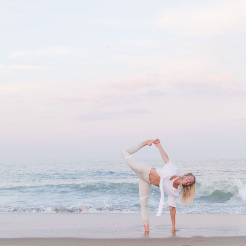 Jessie Benson doing yoga on a beach at sunset, balancing on one leg.