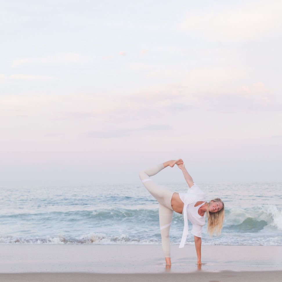 Jessie Benson doing yoga on a beach at sunset, balancing on one leg.
