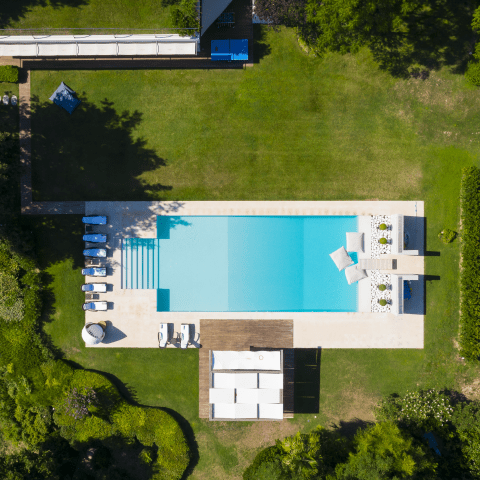 Aerial view of a modern outdoor swimming pool with surrounding greenery.