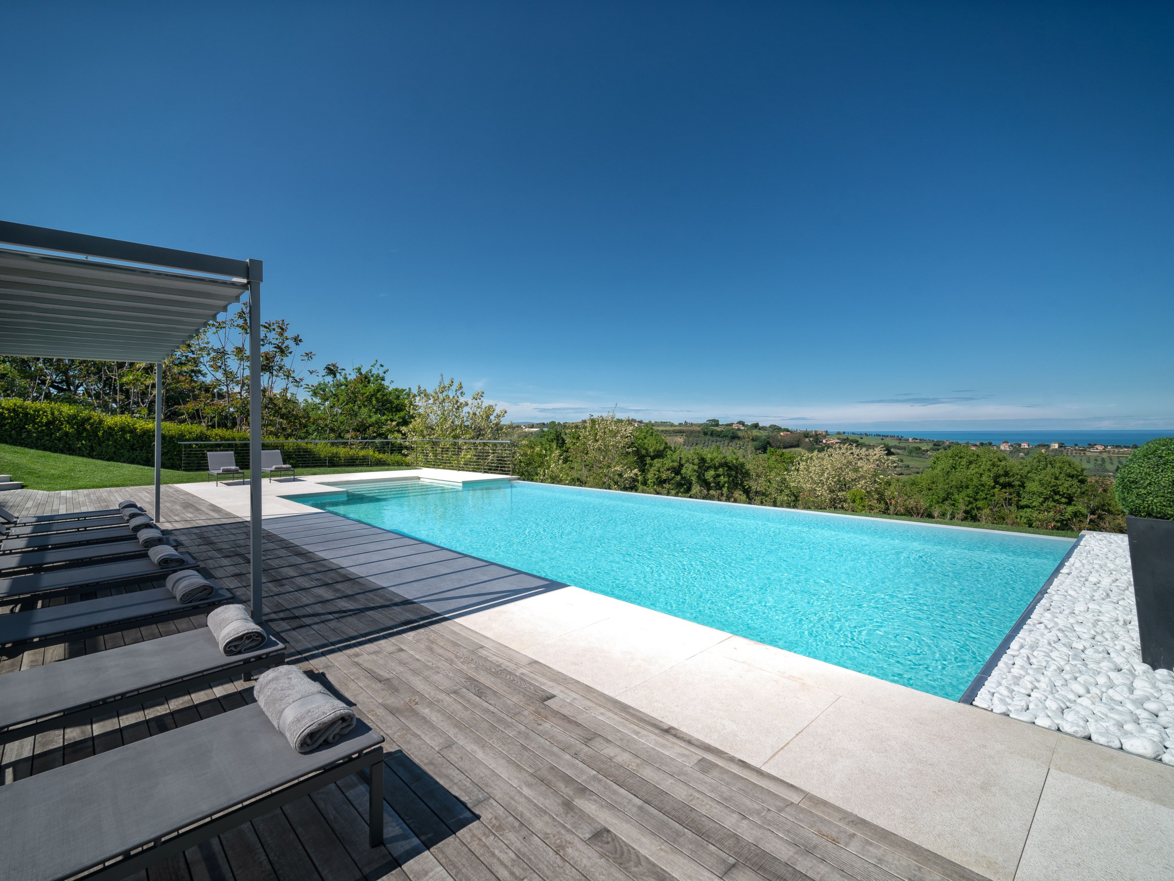 Infinity pool with deck chairs and ocean view.