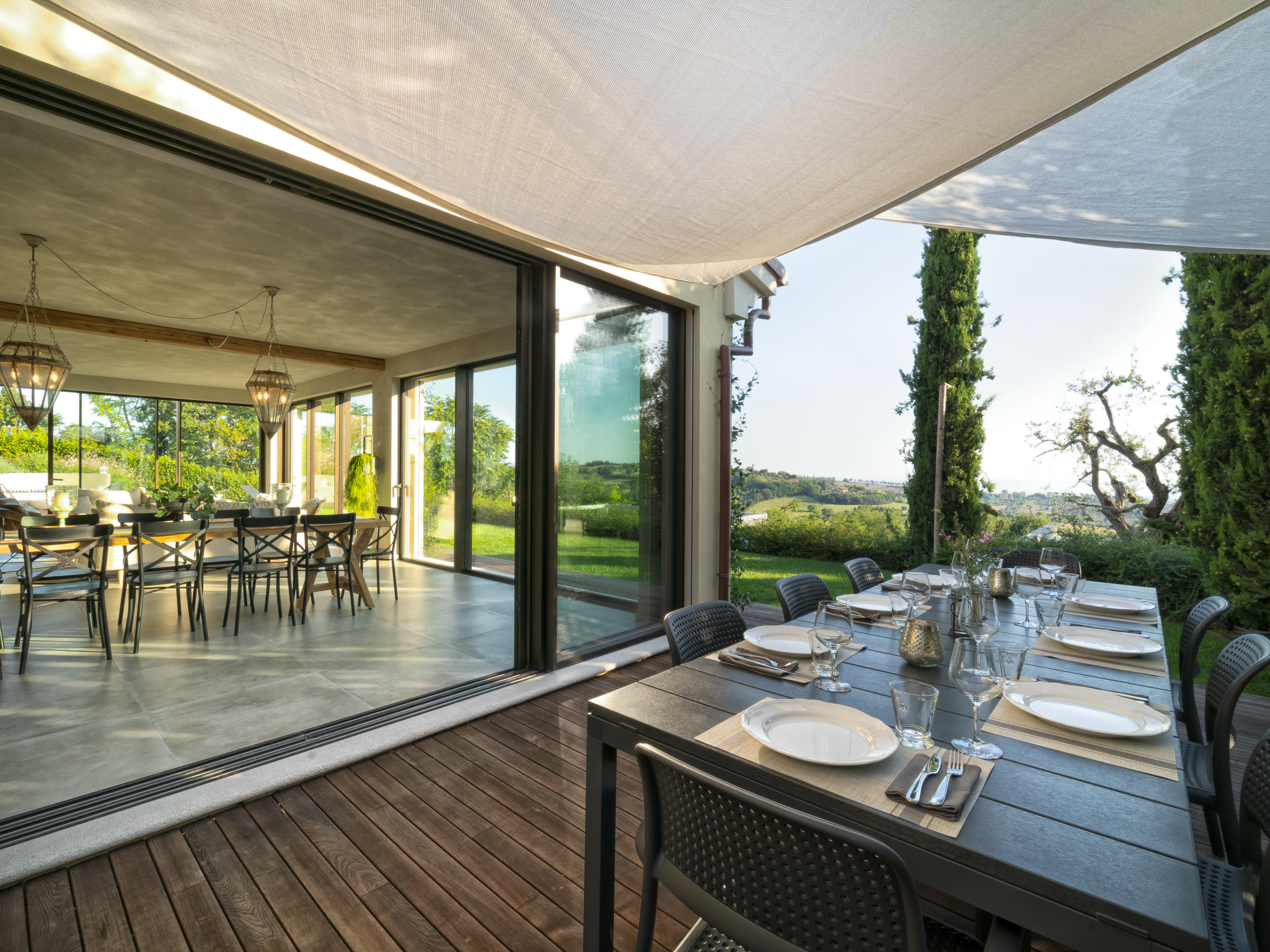 Indoor dining area leads to outdoor table on patio with scenic view.