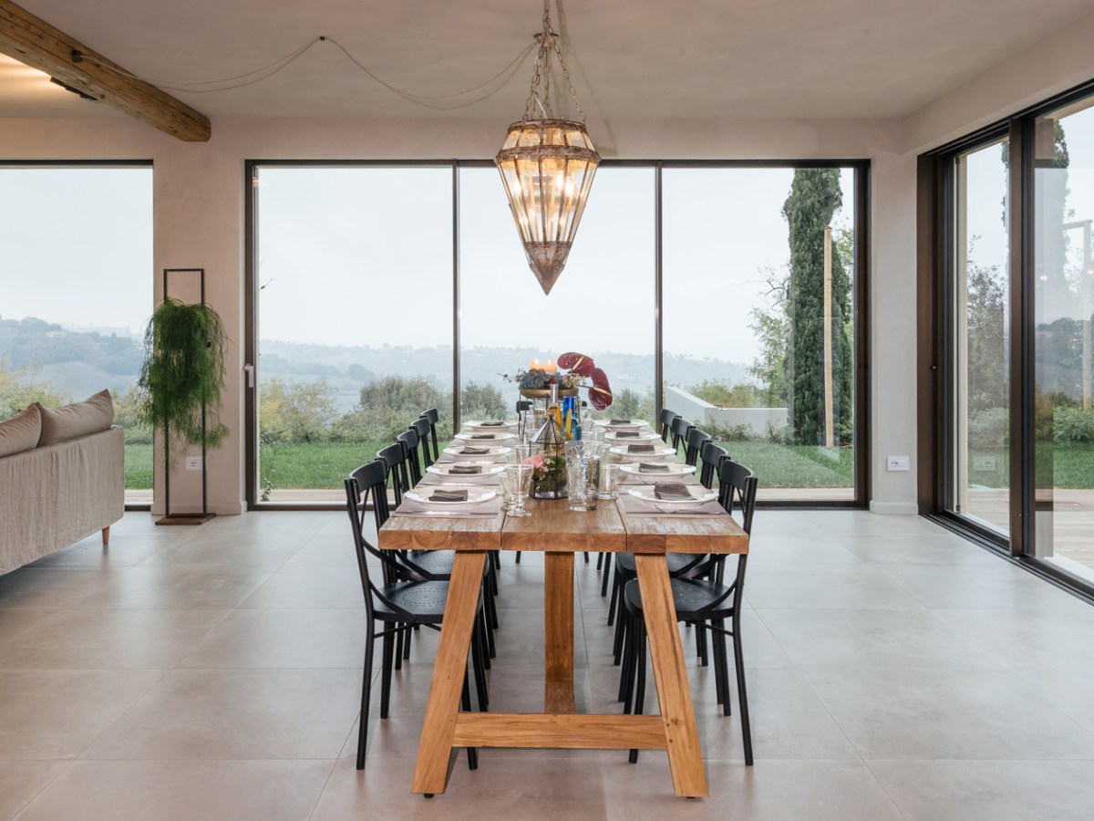Elegant dining room with a long wooden table, black chairs, and large windows overlooking a garden.