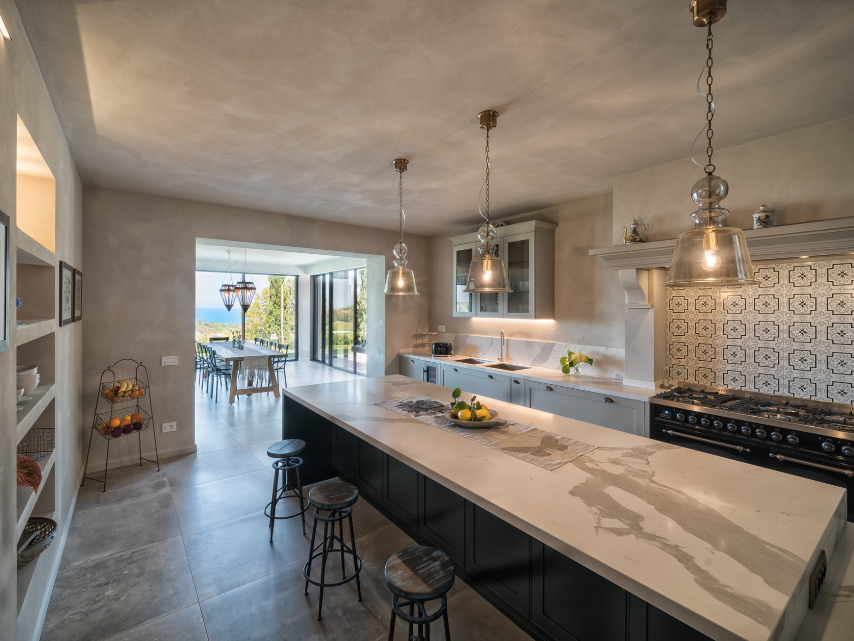 Spacious kitchen with a long island, stools, pendant lights, and a view of a dining area.