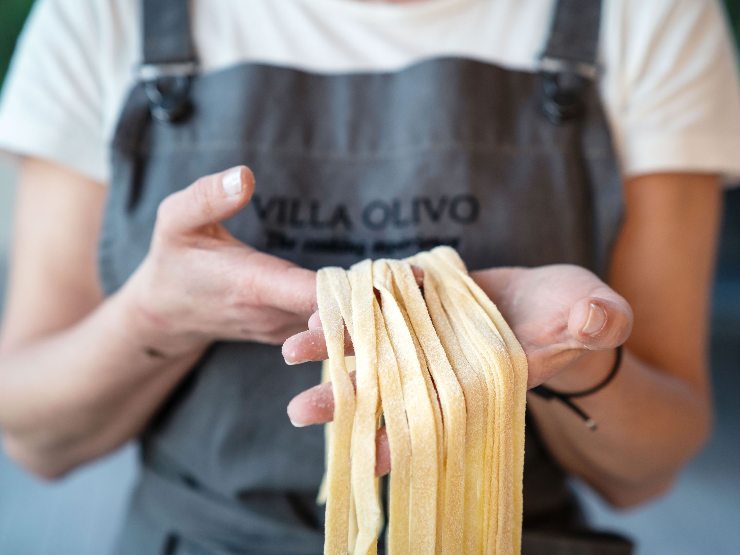 Person holding uncooked pasta strands with both hands.