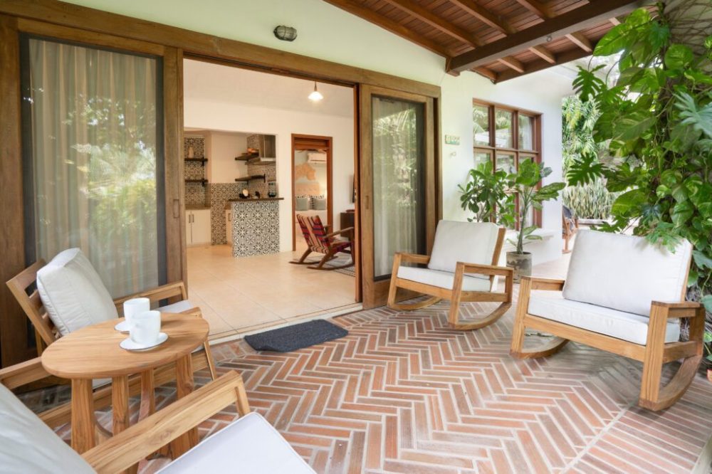 Cozy patio with wooden furniture and a view into a modern living room.