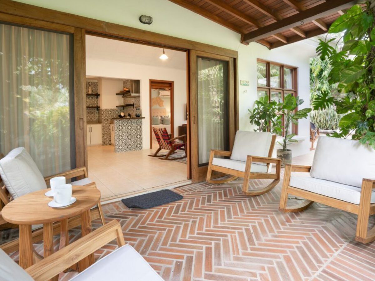 Cozy patio with wooden furniture and a view into a modern living room.