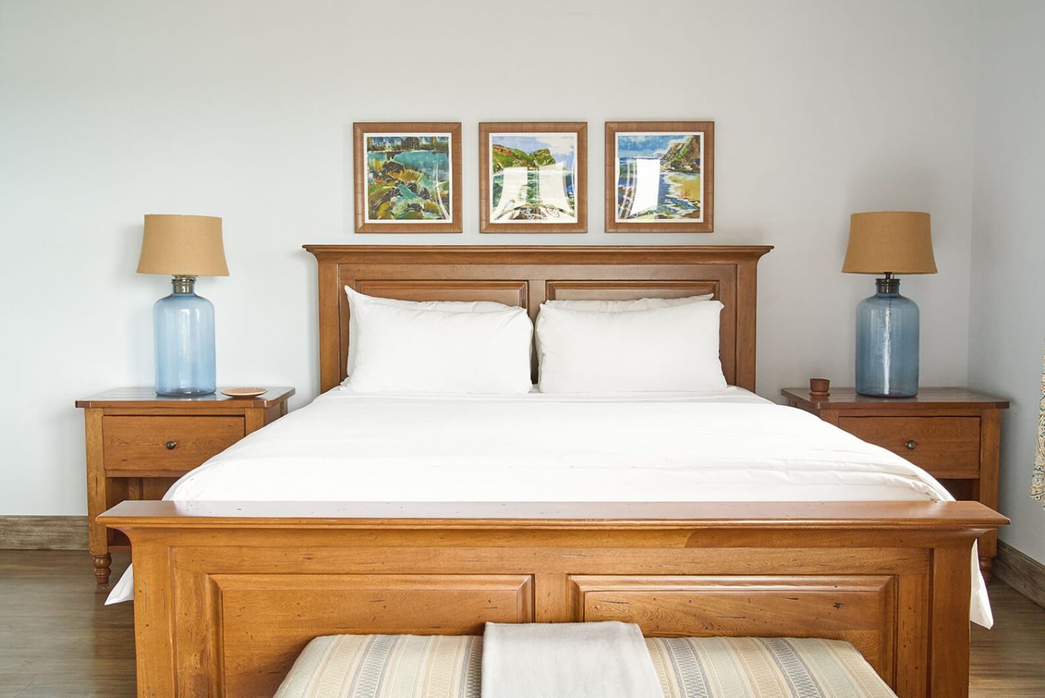 Wooden bed with white linens, flanked by blue lamps on nightstands.