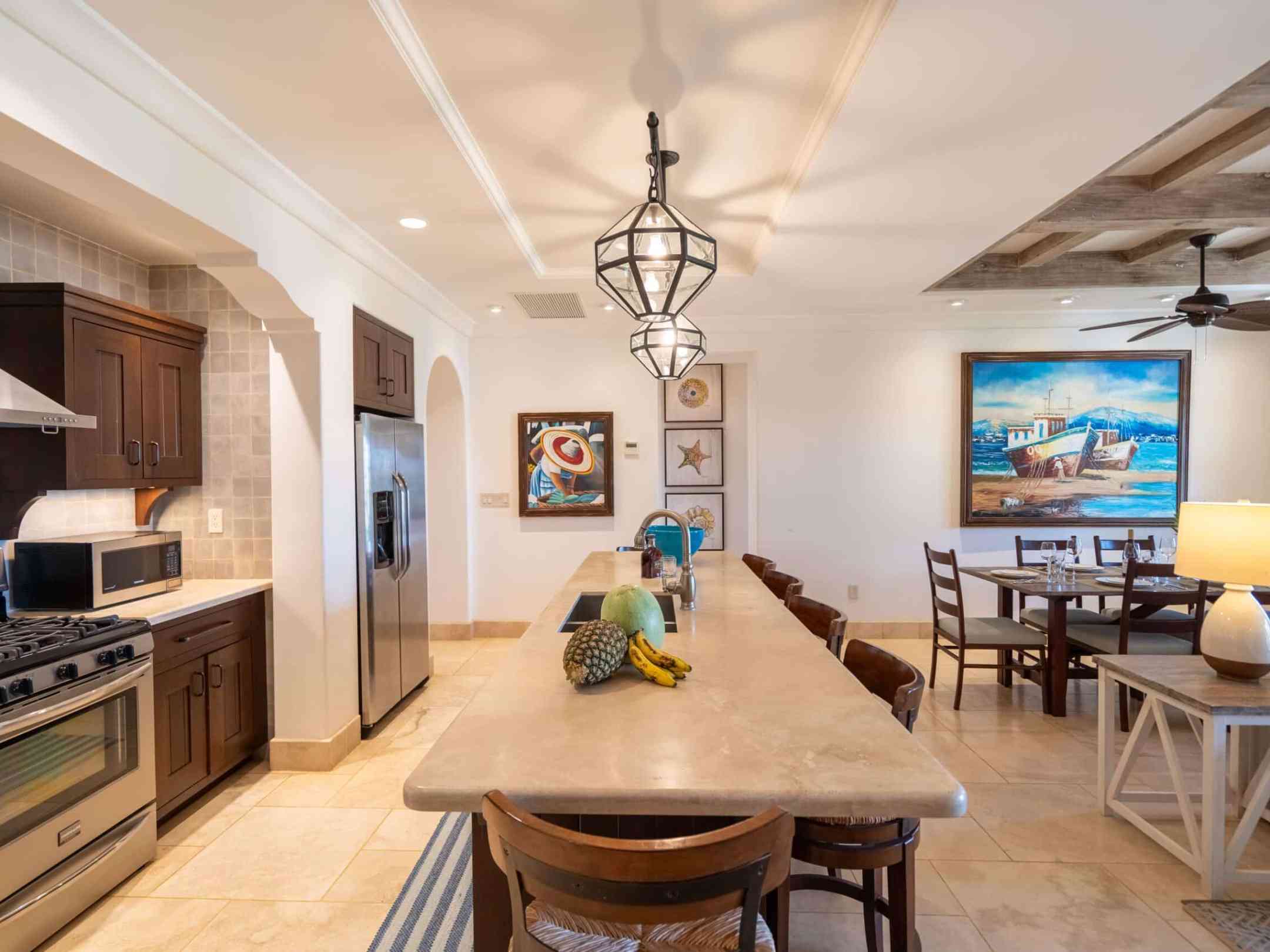 Spacious kitchen and dining room with island, modern appliances, and artwork on walls.