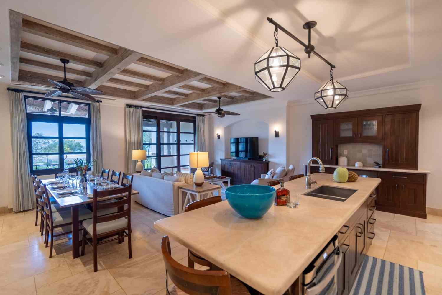 Spacious kitchen and living area with island, dining table, and large windows.