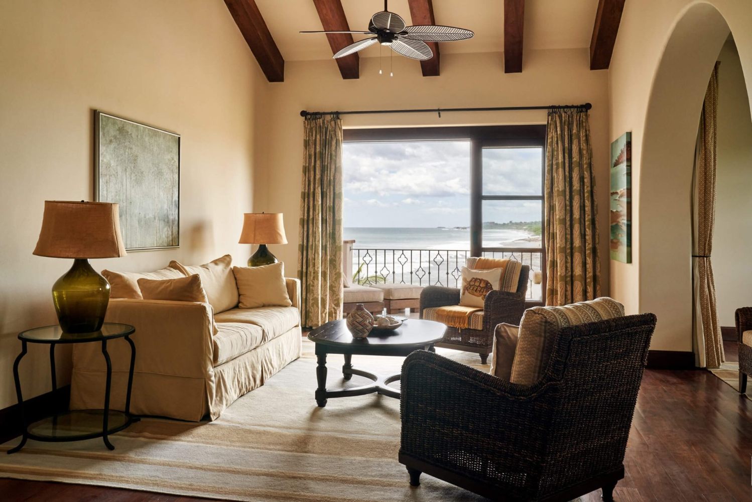 Cozy living room with sofas, armchairs, and ocean view through large window.