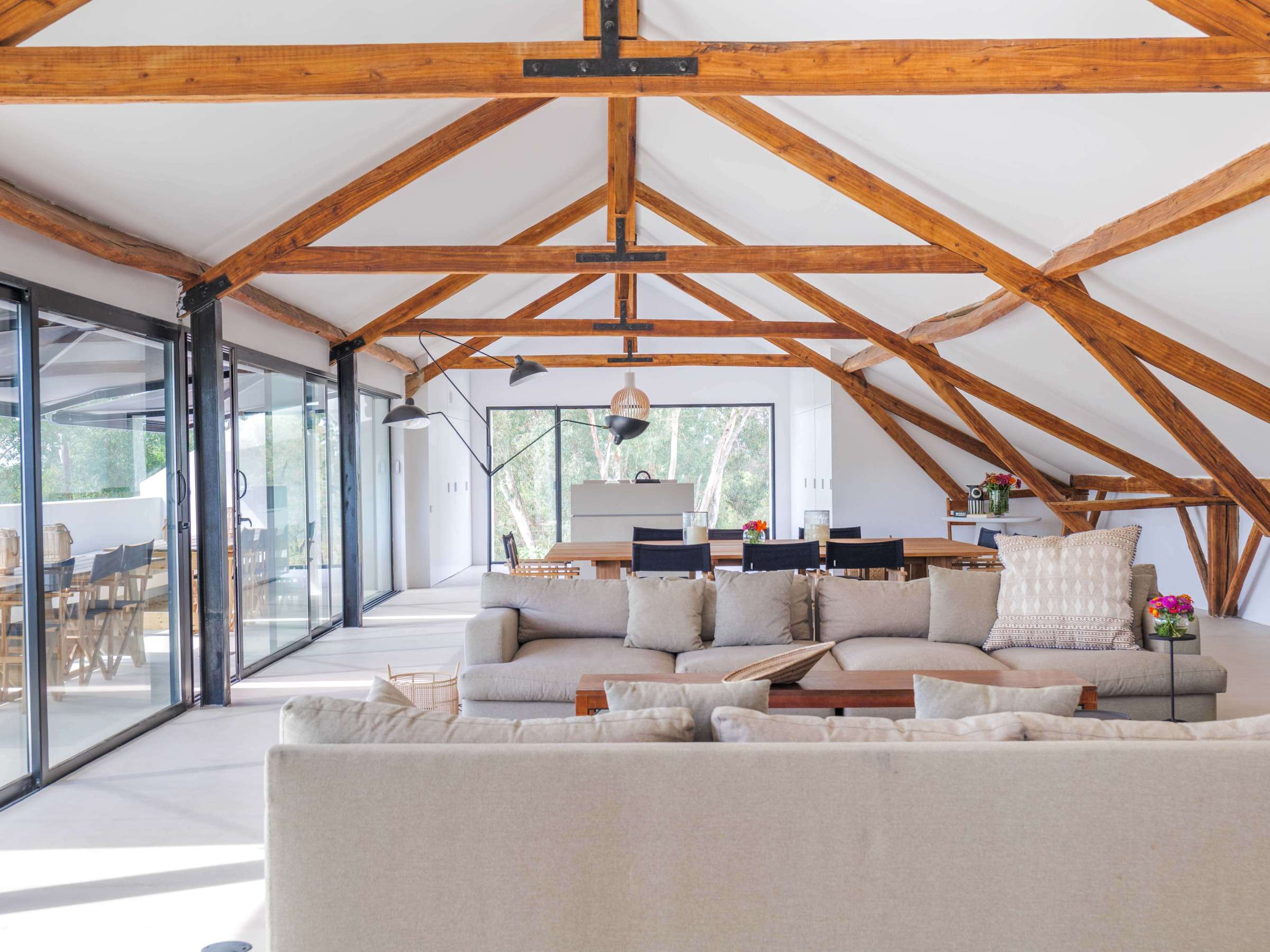 Spacious loft with exposed beams, modern furniture, and large windows.