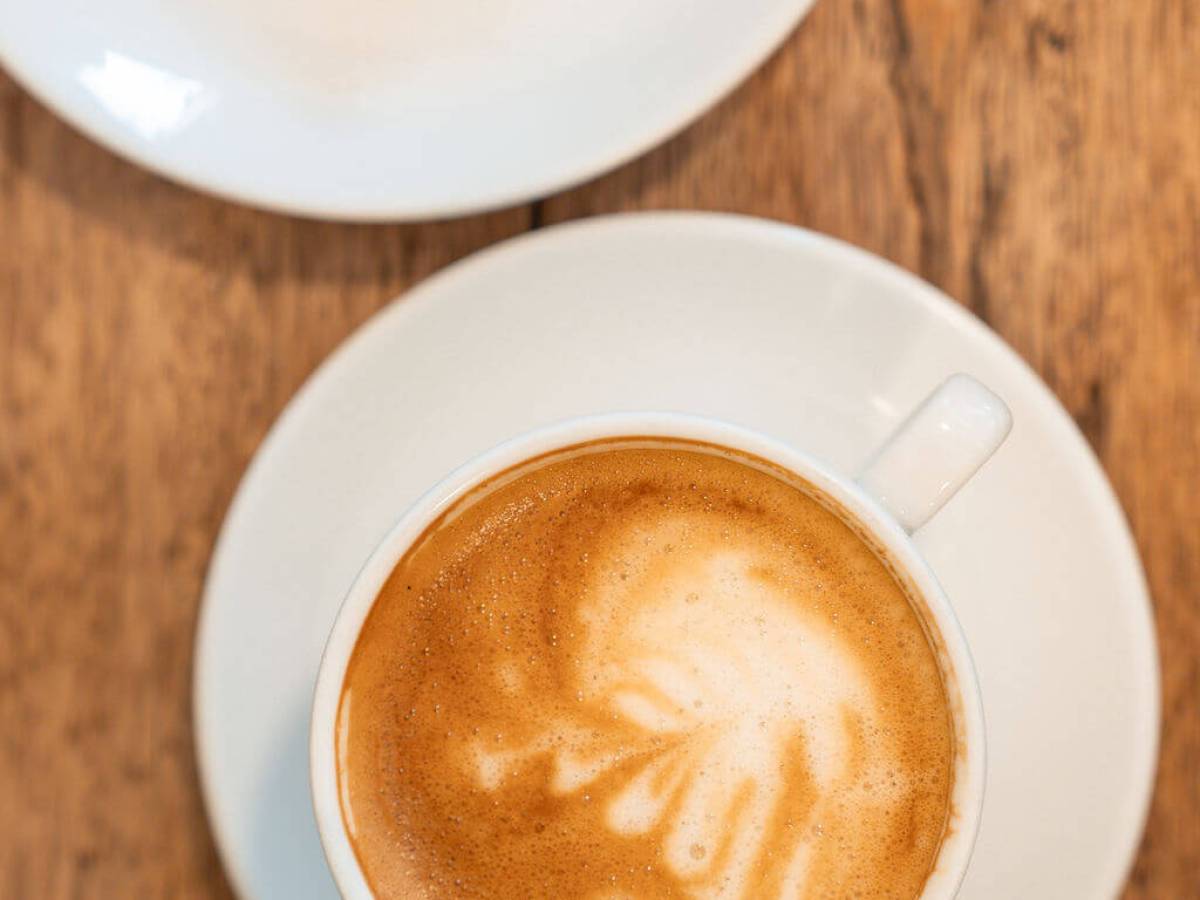 Cup of cappuccino on a wooden table with a plate of chocolate.