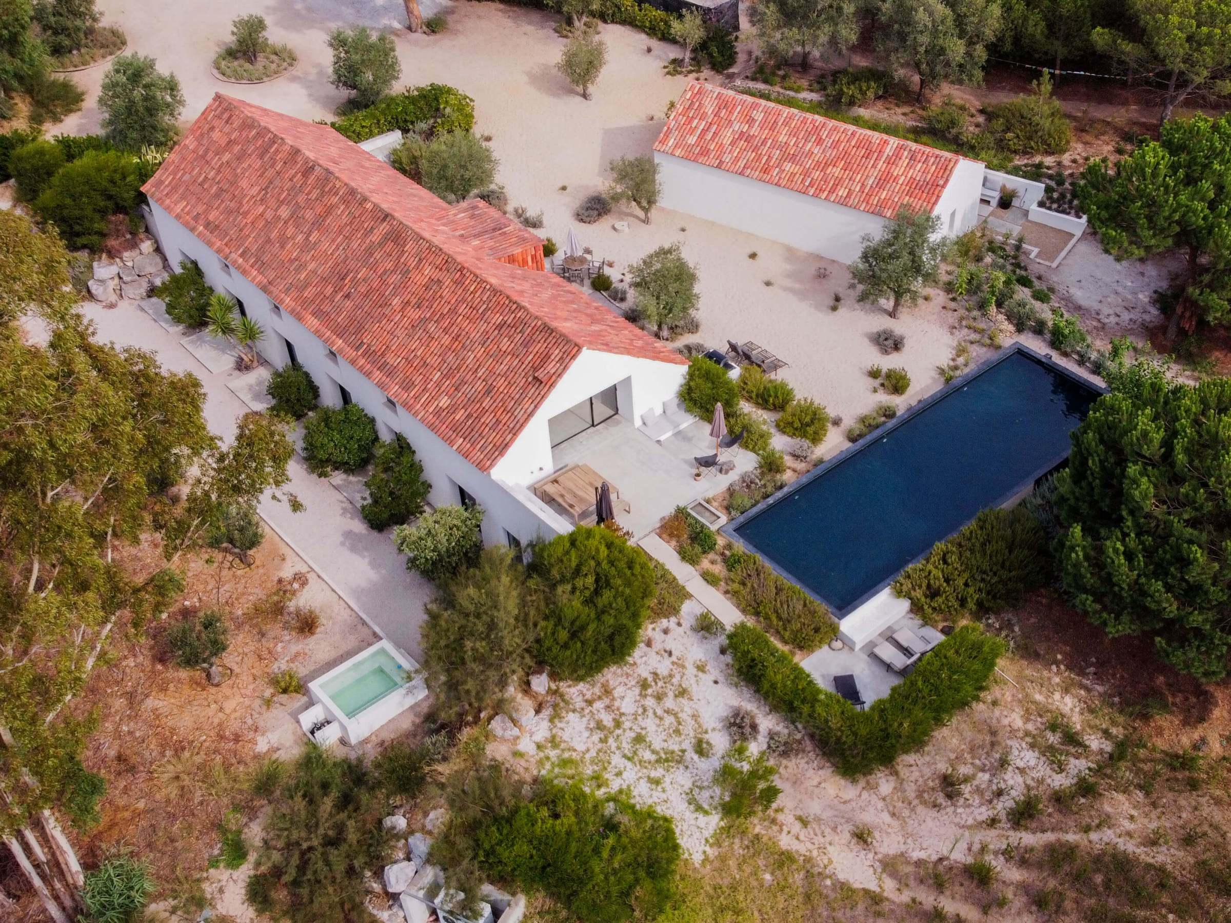Aerial view of a modern house with a rectangular pool and red-tiled roof.