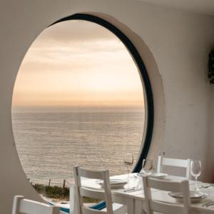 Round window with ocean view from a minimalistic dining area.