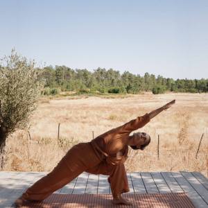Person practicing yoga on a deck in open field.